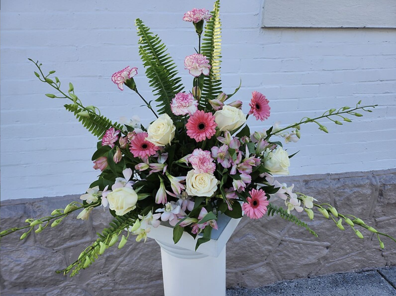 Pink and white floral arrangement in a white pedestal vase