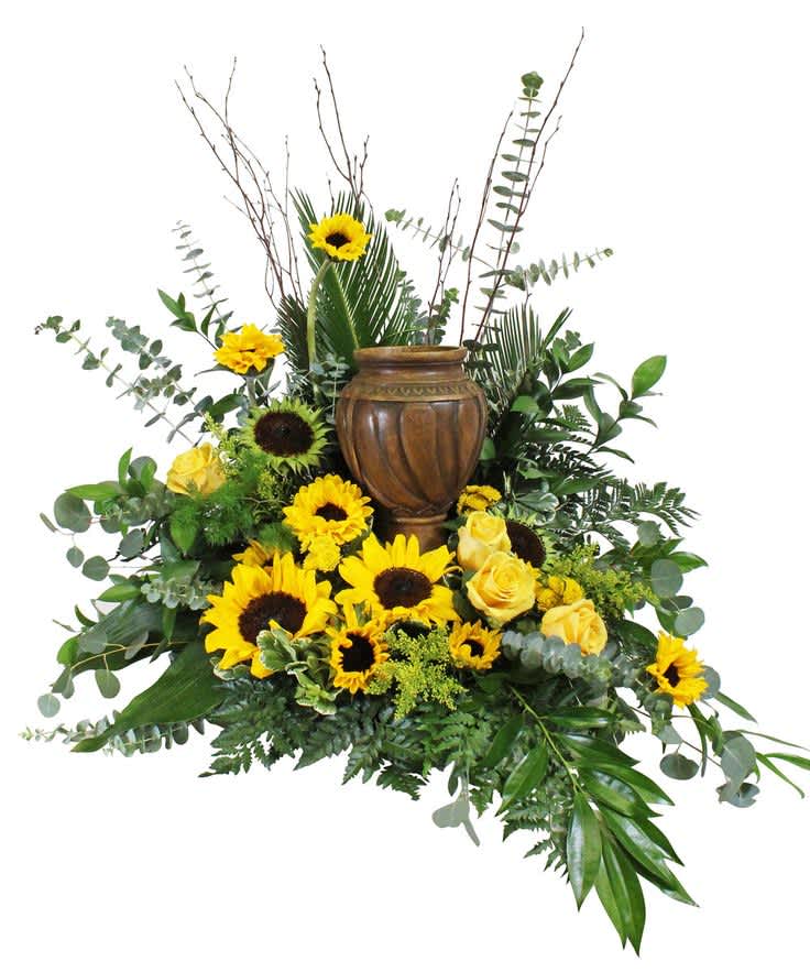 Sunflower and yellow rose arrangement around a brown urn