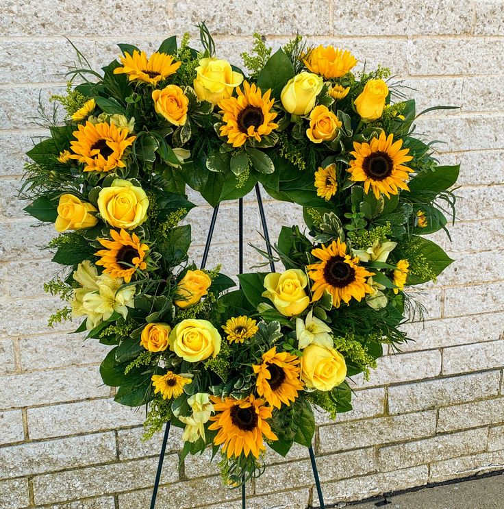 Heart-shaped floral wreath with yellow roses and sunflowers on a stand