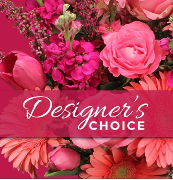 Pink floral arrangement with roses and daisies behind a Designer's Choice banner