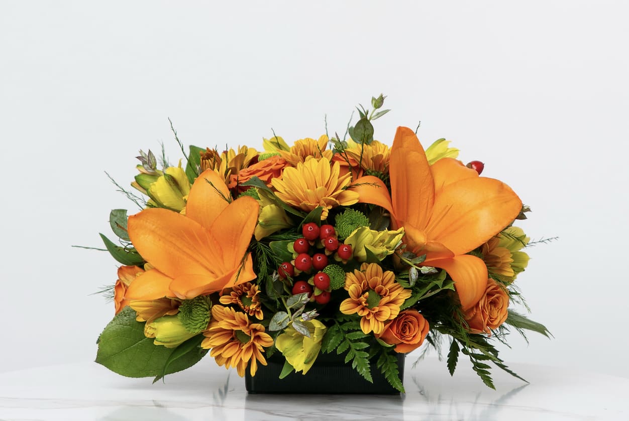 Orange and yellow floral arrangement in a black container