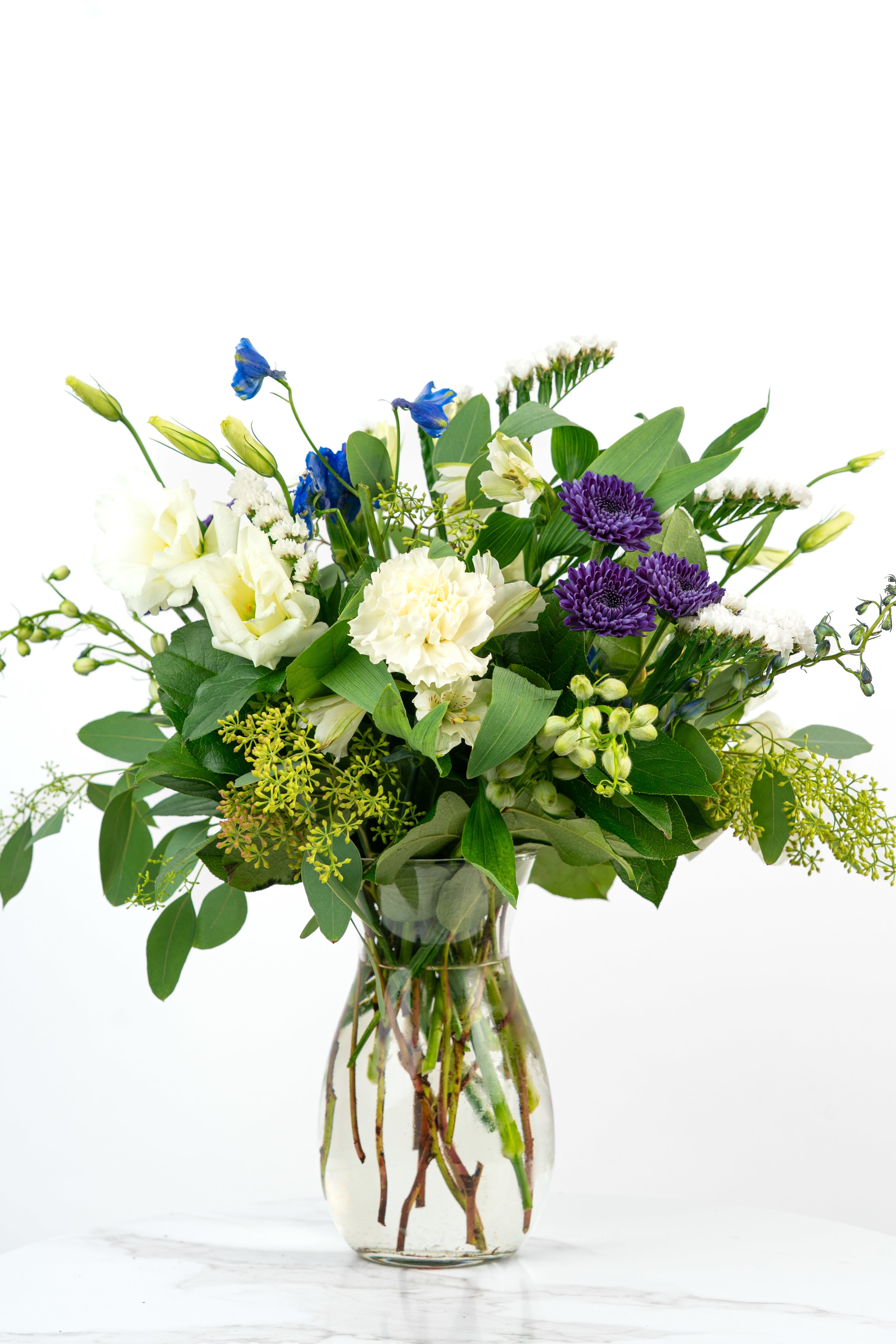 Our Birthday Collection: Coolest Birthday Wishes [Deluxe Blooms] - A Valparaiso Best Seller, the Coolest Blooming Birthday Wishes arrangement with Deluxe Blooms is bursting with cool-toned color and fresh-picked charm to make someone's special day unforgettable. Send birthday wishes with this one of a kind arrangement styled just for your order. Because we always use the freshest blooms, your final arrangement may not look exactly as pictured due to seasonal availability.