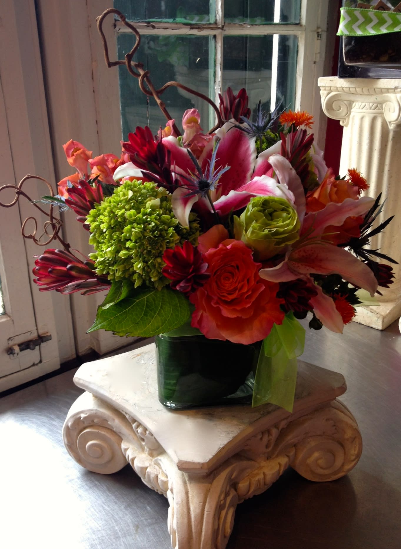 Colorful mixed flower arrangement in a dark green vase