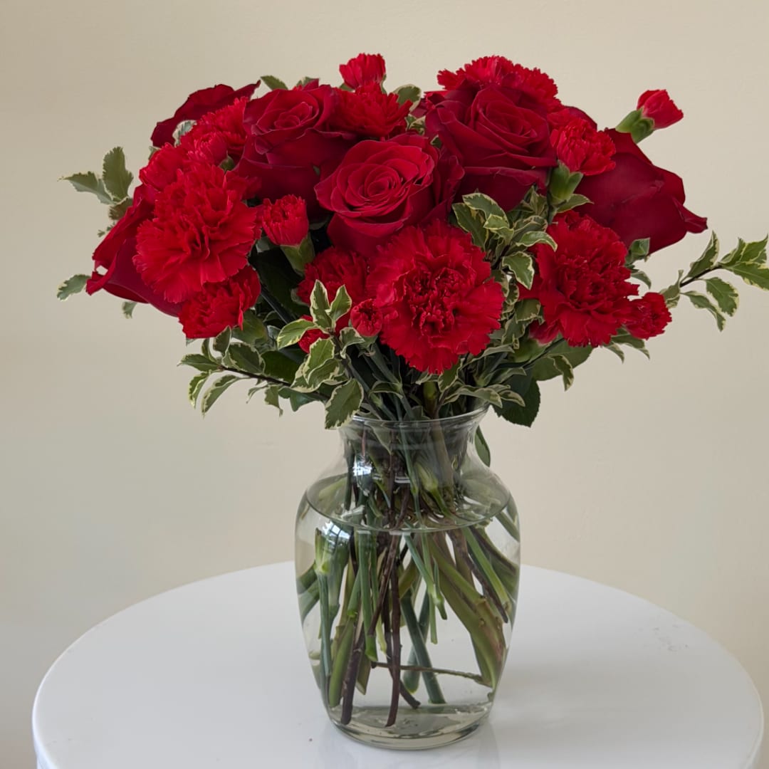 Red roses and carnations in a clear glass vase