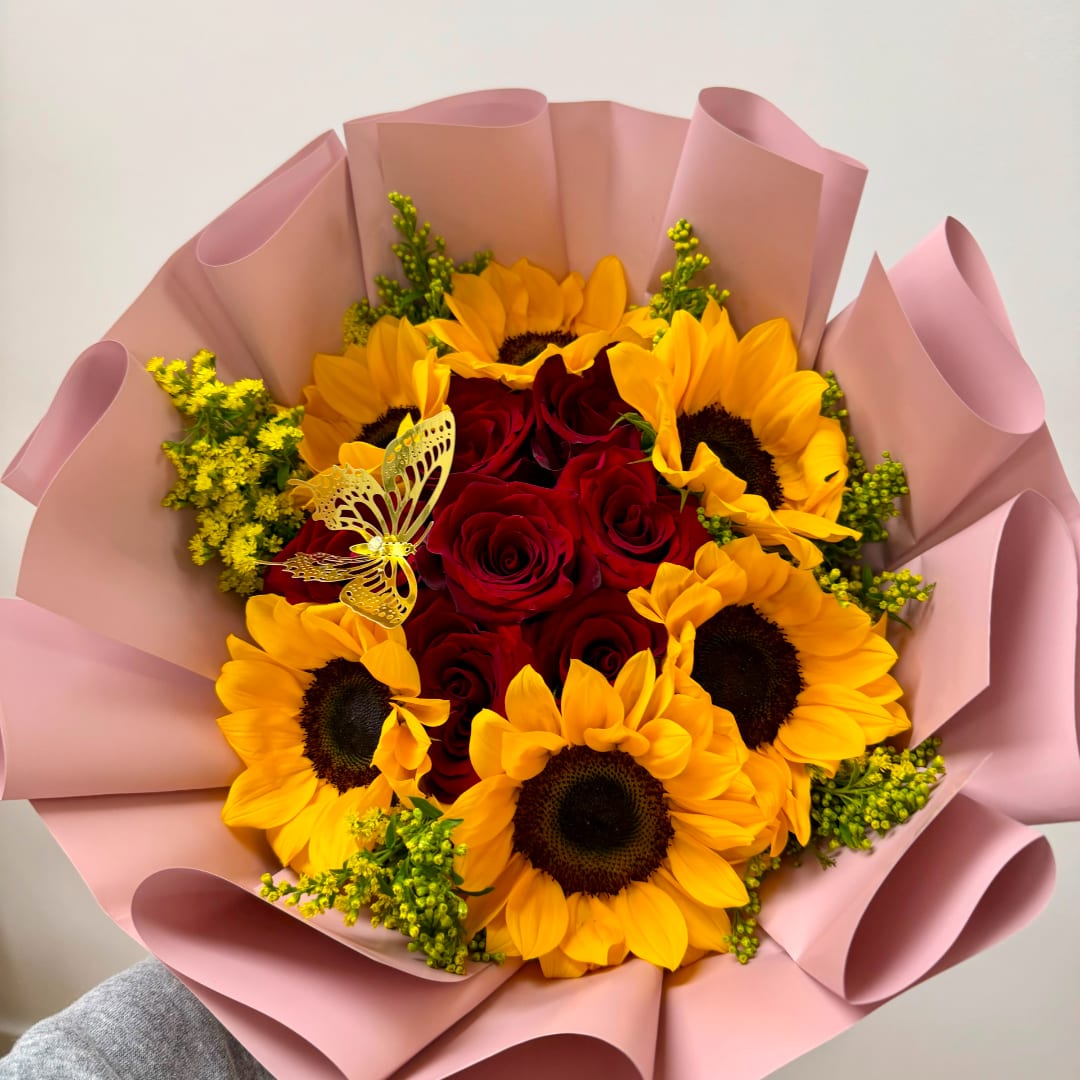 Bouquet of red roses and yellow sunflowers wrapped in pink paper