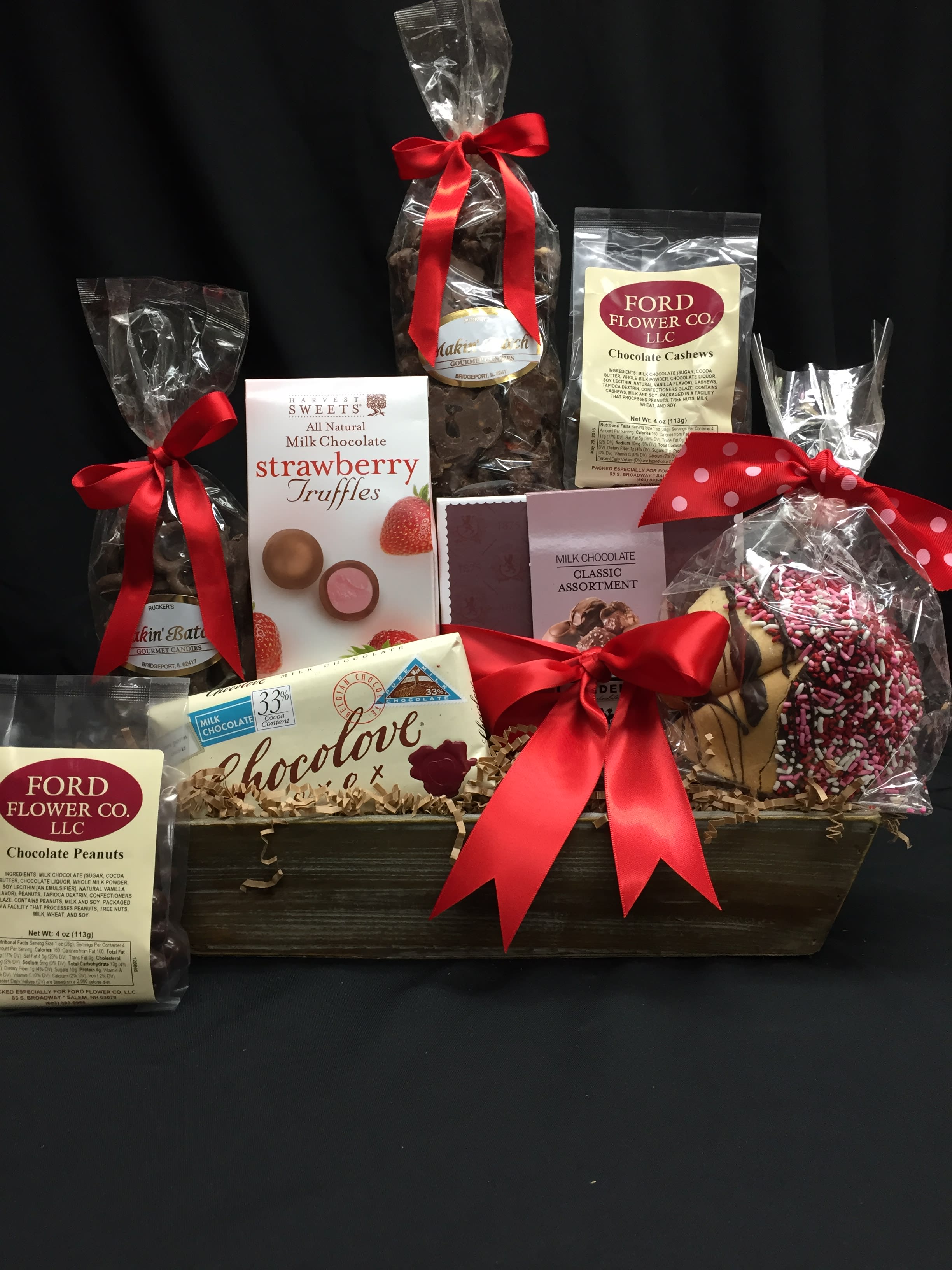Wooden gift basket filled with assorted boxed and bagged chocolates tied with red ribbons
