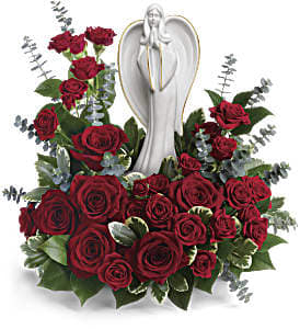 Low arrangement of red roses surrounding a white angel figurine