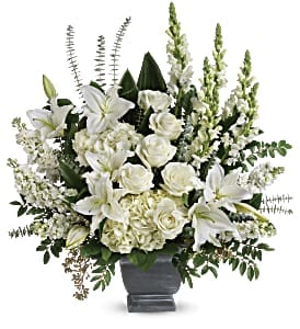 Tall white arrangement of lilies, roses, and hydrangeas in a gray pedestal vase