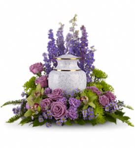 Cremation urn surrounded by lavender and purple flowers with taller blooms rising behind.
