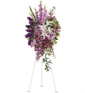 Tall purple and lavender standing spray with white lilies on a white easel.