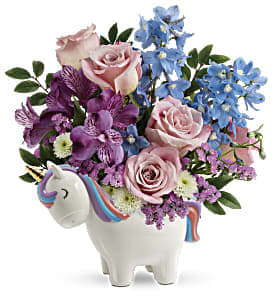Pastel roses and purple blooms in a white unicorn-shaped ceramic container
