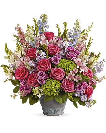 Abundant pink and purple mixed flower arrangement with green hydrangeas in a gray ceramic pot