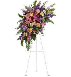 Tall standing spray of pink lilies, roses, and mixed flowers on a white easel