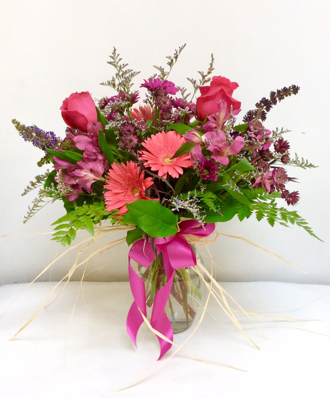 Pink and purple mixed bouquet in a glass vase with a ribbon