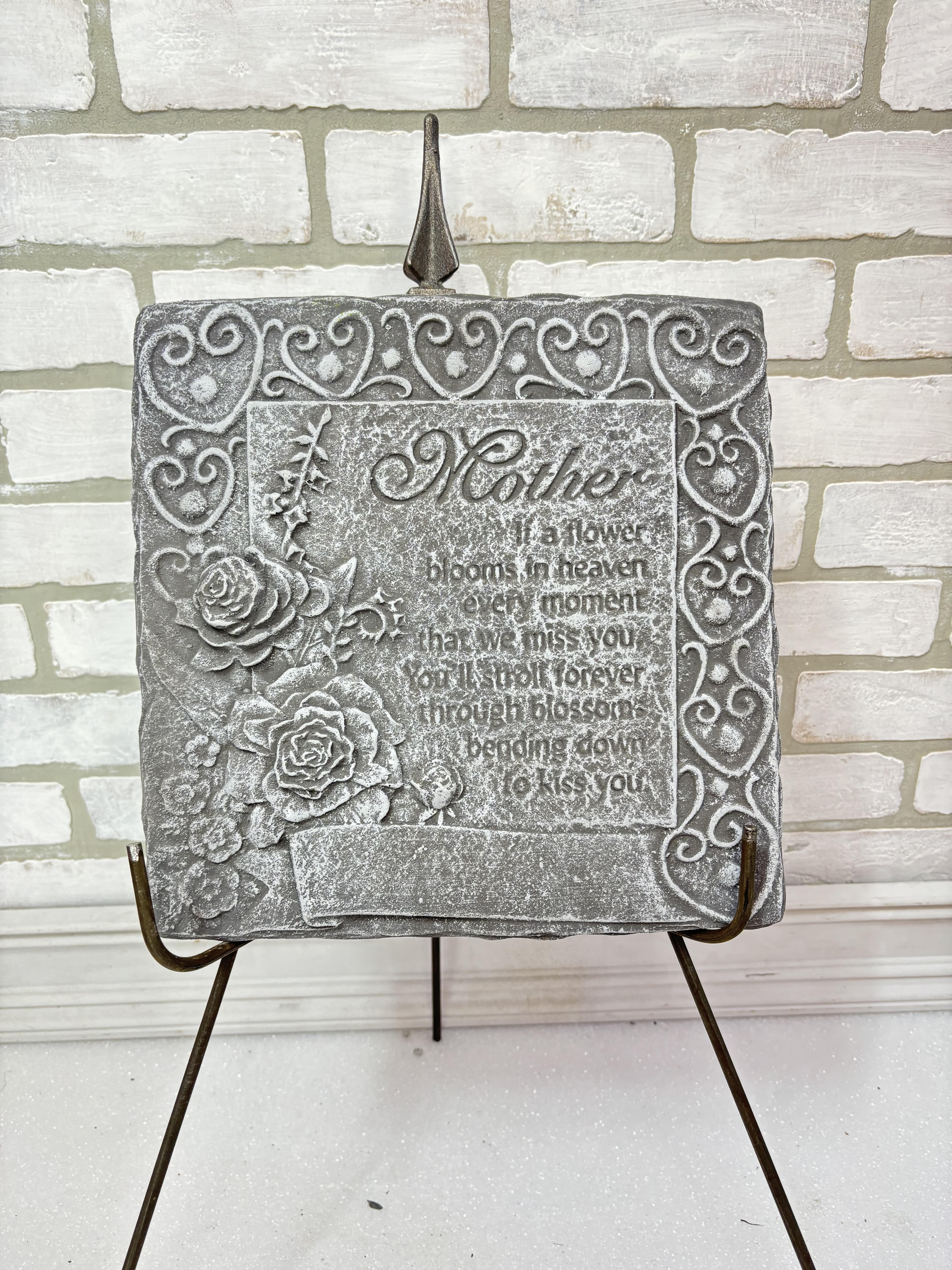 Gray memorial plaque with roses on a metal stand