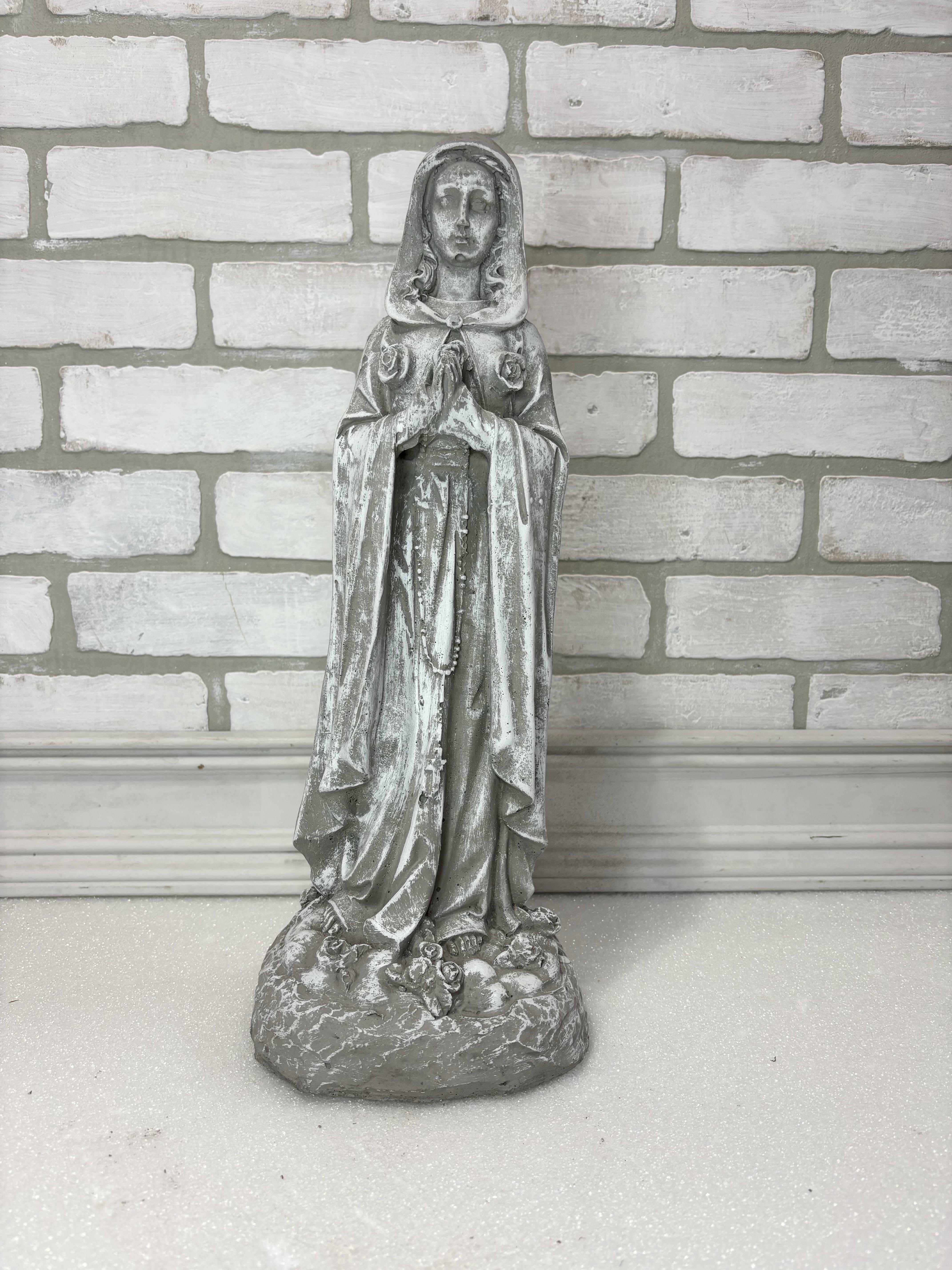 Weathered gray religious statue of a praying woman on a base