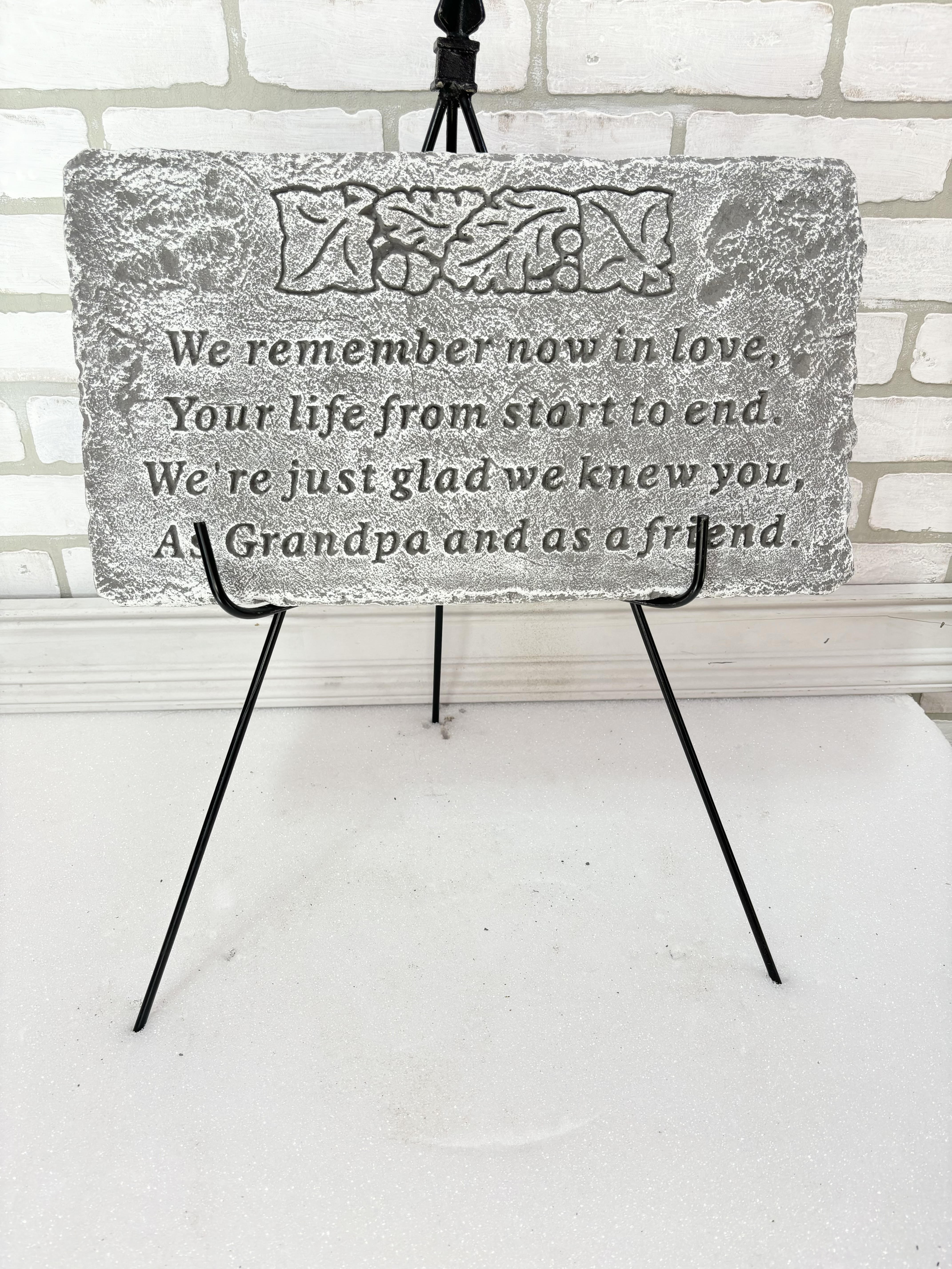 Gray memorial plaque on a black easel with engraved text