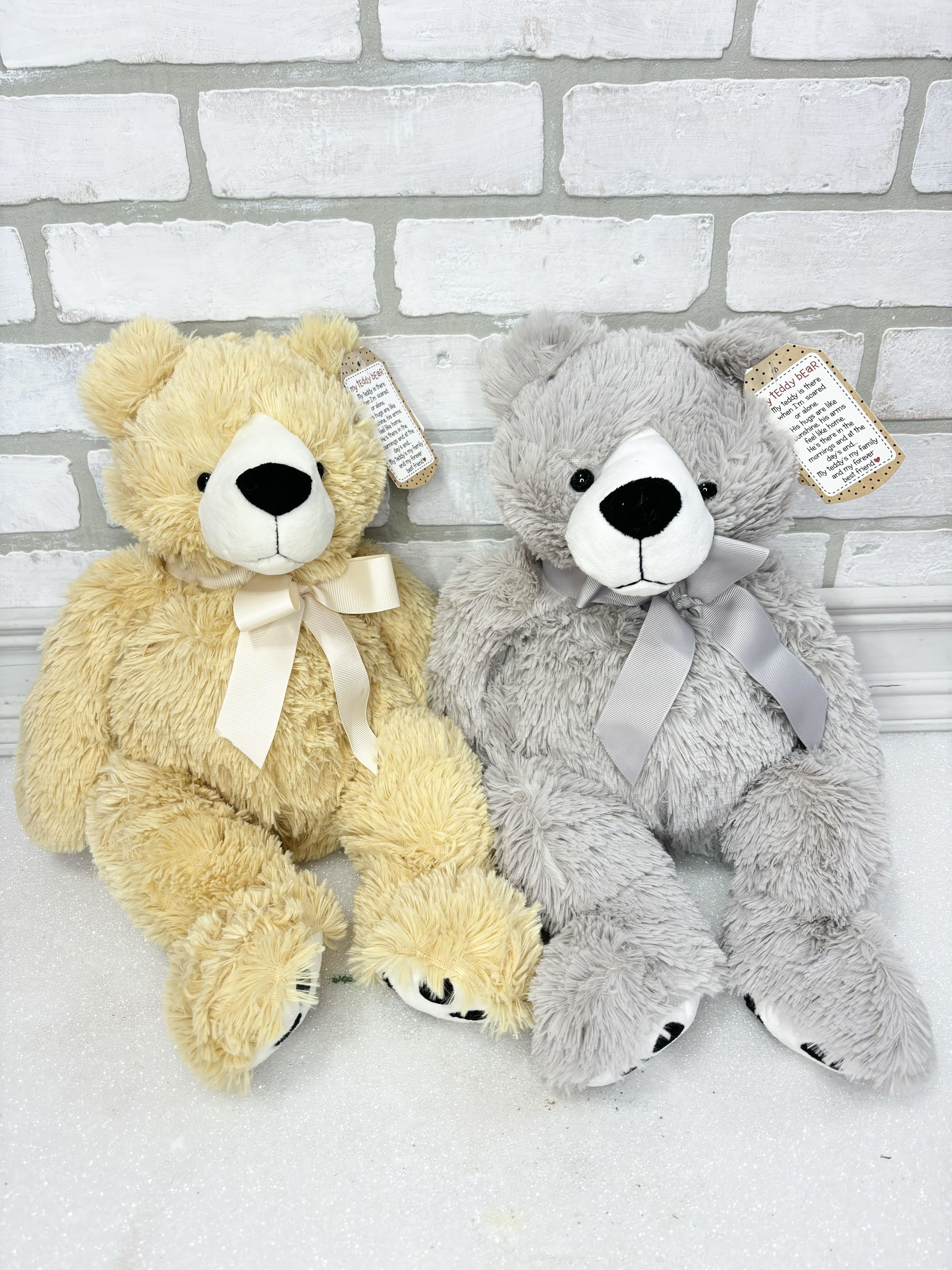 Two plush teddy bears with ribbon bows, one yellow and one gray