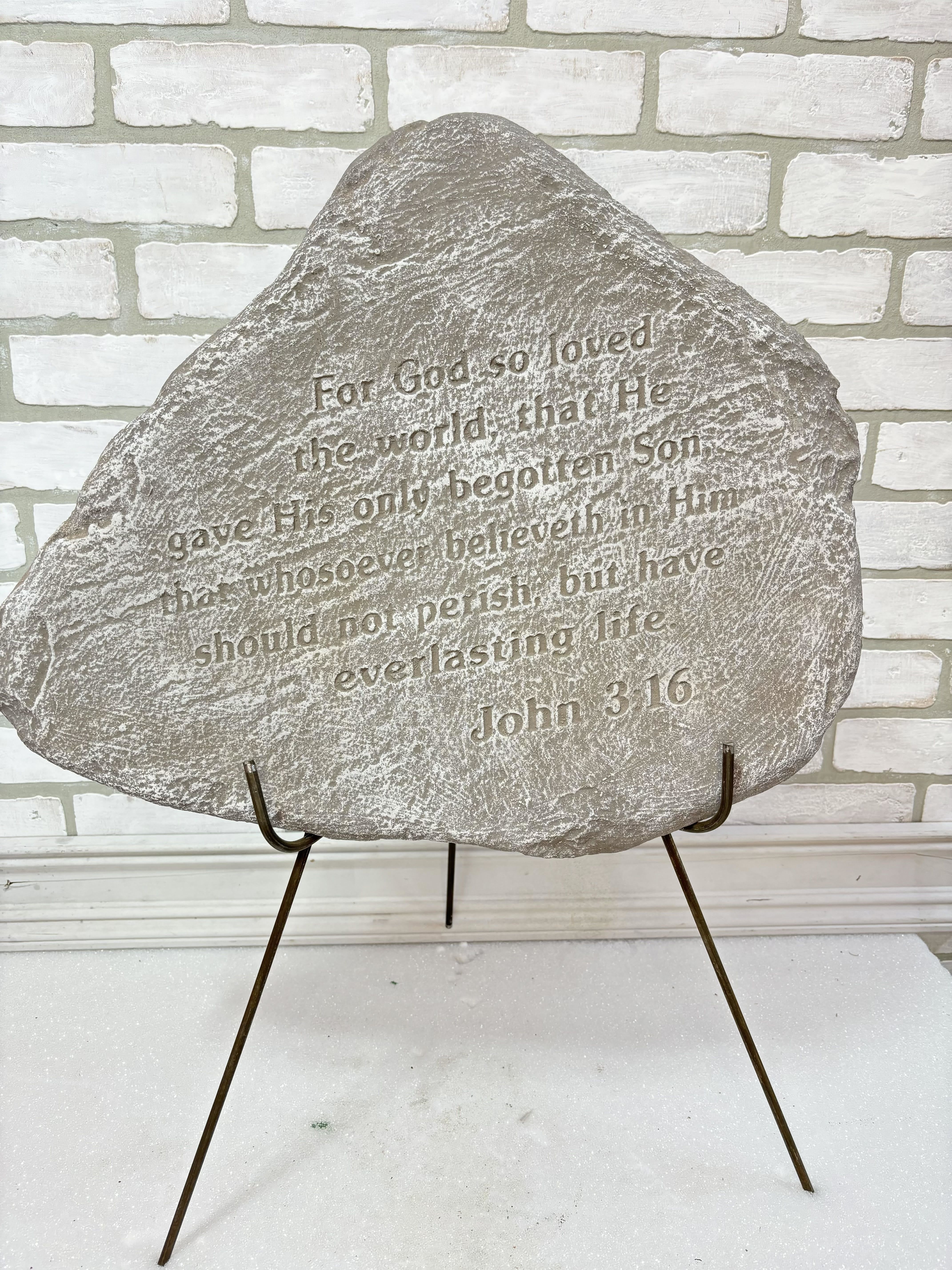 Engraved memorial stone on a metal stand with Bible verse text