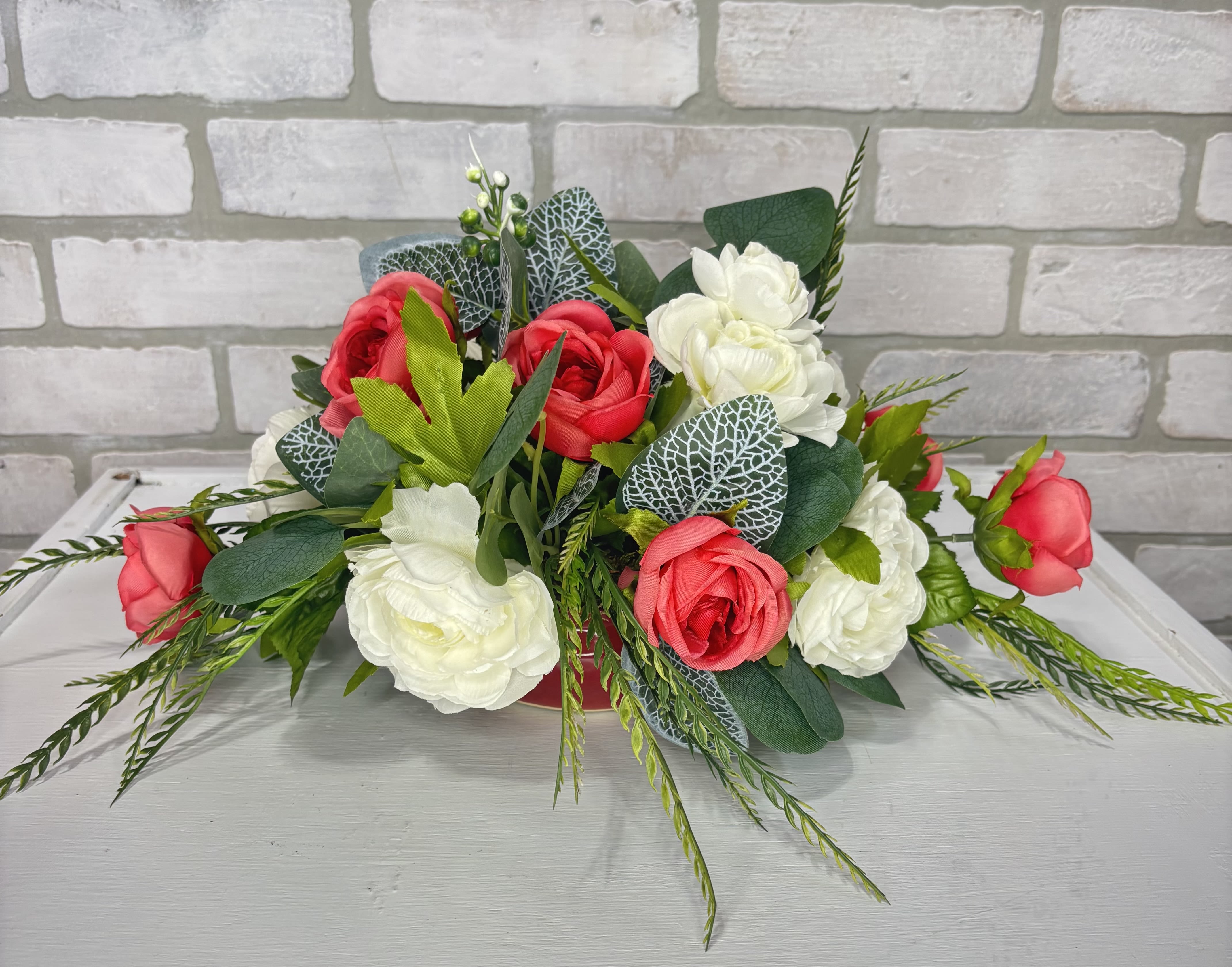 Arrangement of red and white roses with greenery on a table