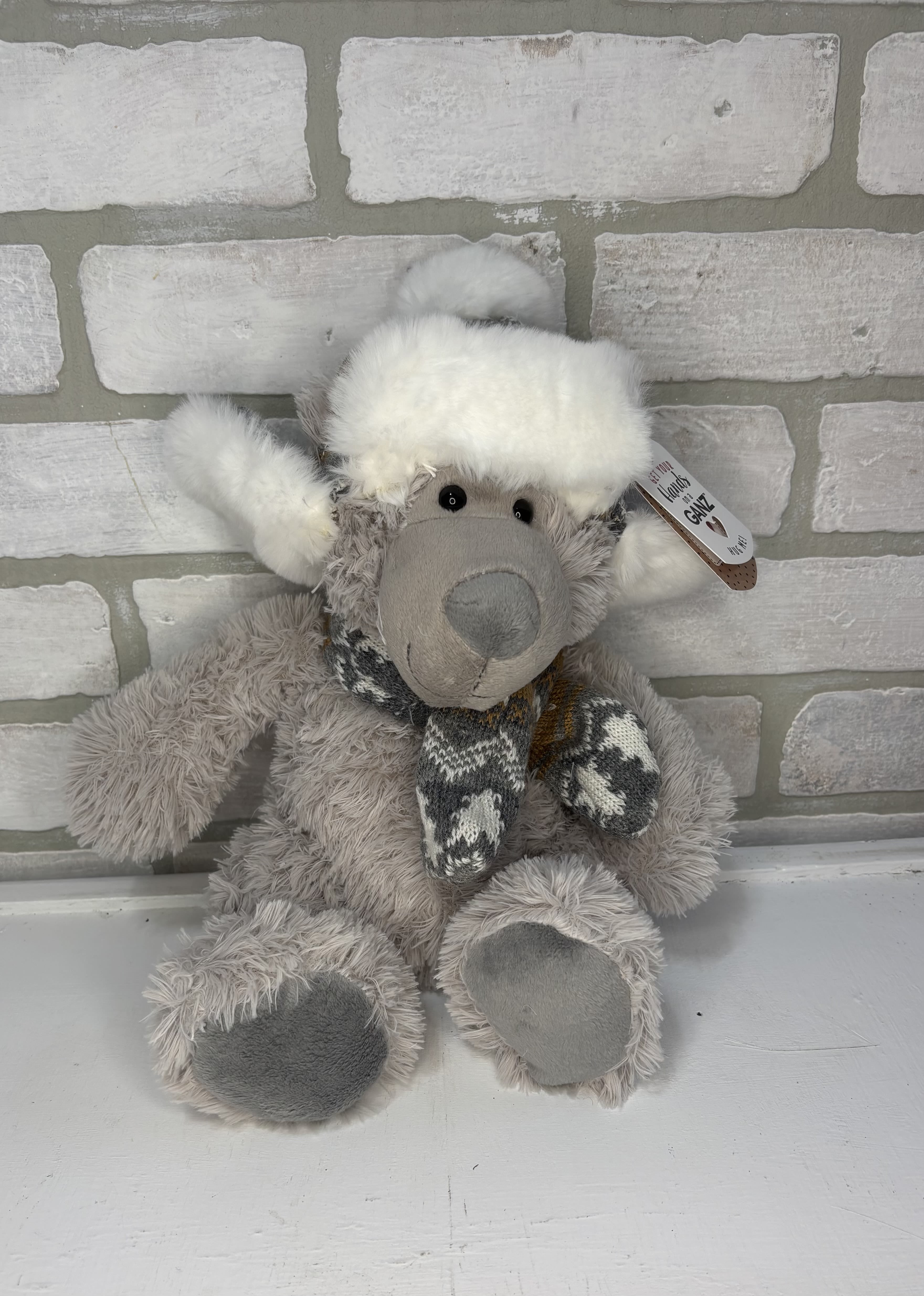 Plush gray teddy bear wearing a white hat and scarf