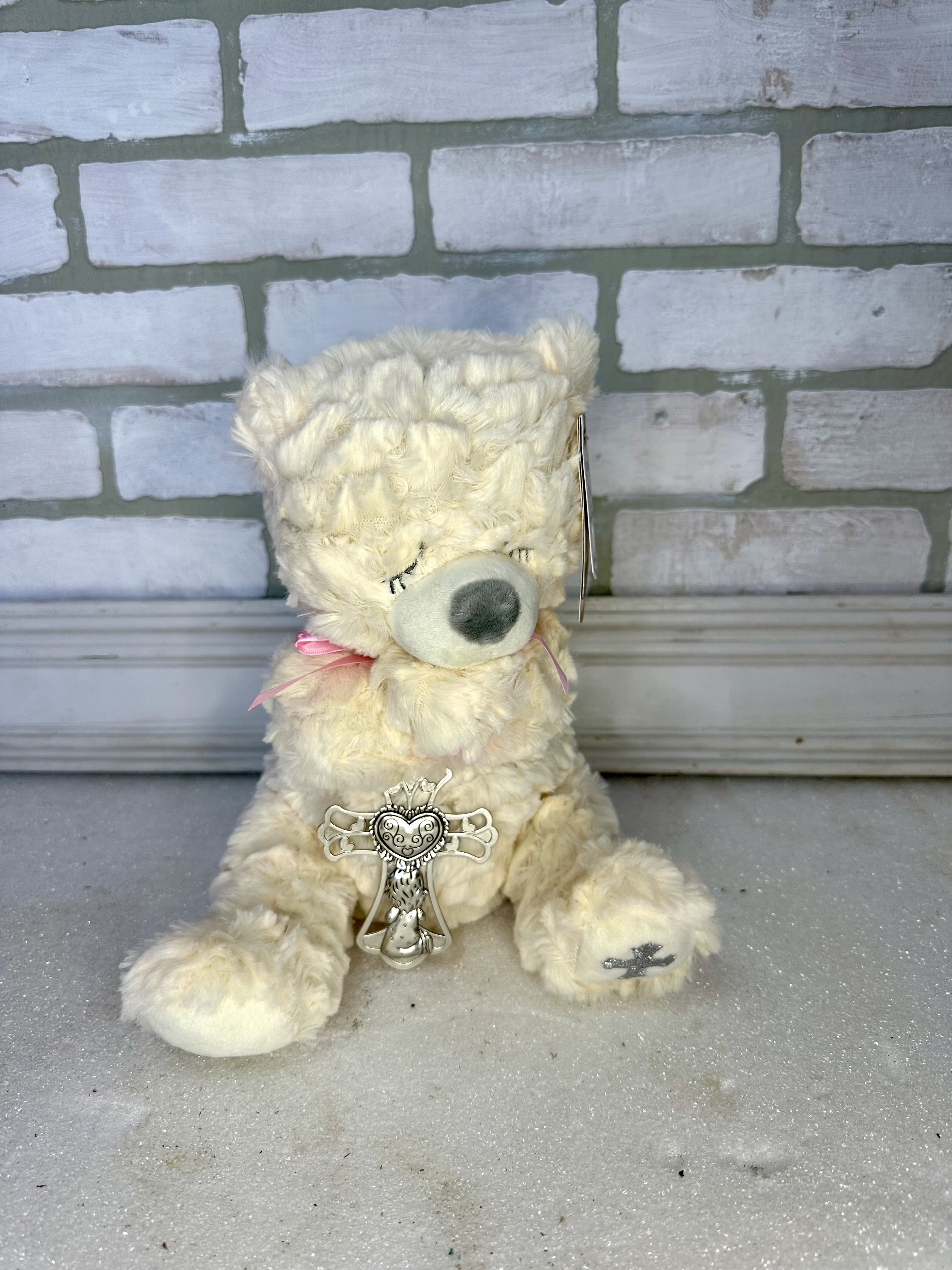Cream teddy bear with a pink ribbon and decorative charm