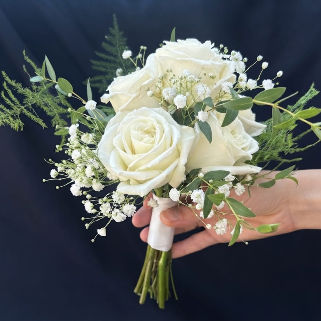 Handheld bouquet of white roses with baby's breath and greenery