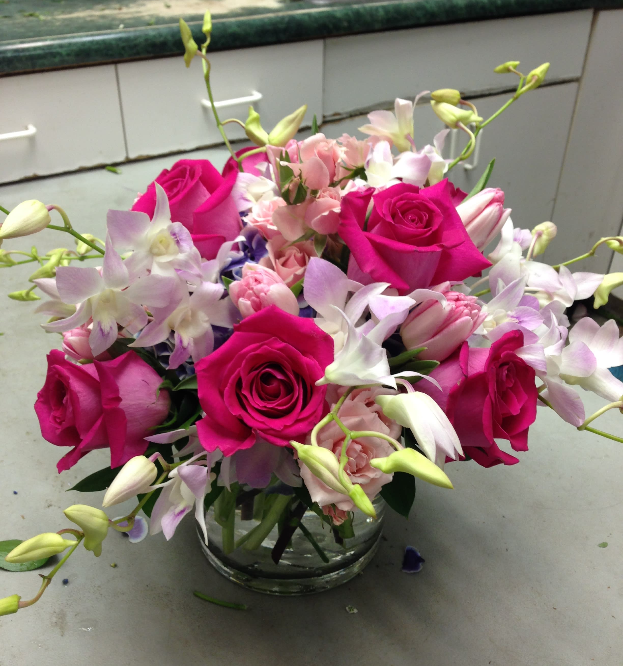 Pink roses and pale orchids arranged in a clear glass vase