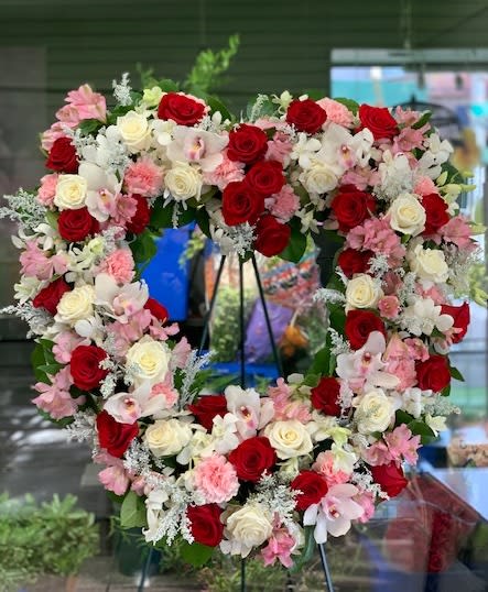 Heart-shaped floral wreath with red, white, and pink roses and orchids