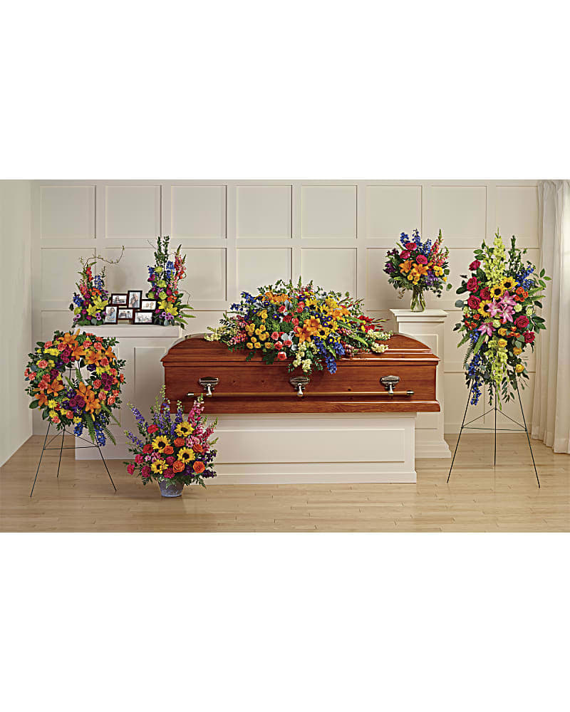Colorful funeral casket spray with standing floral arrangements