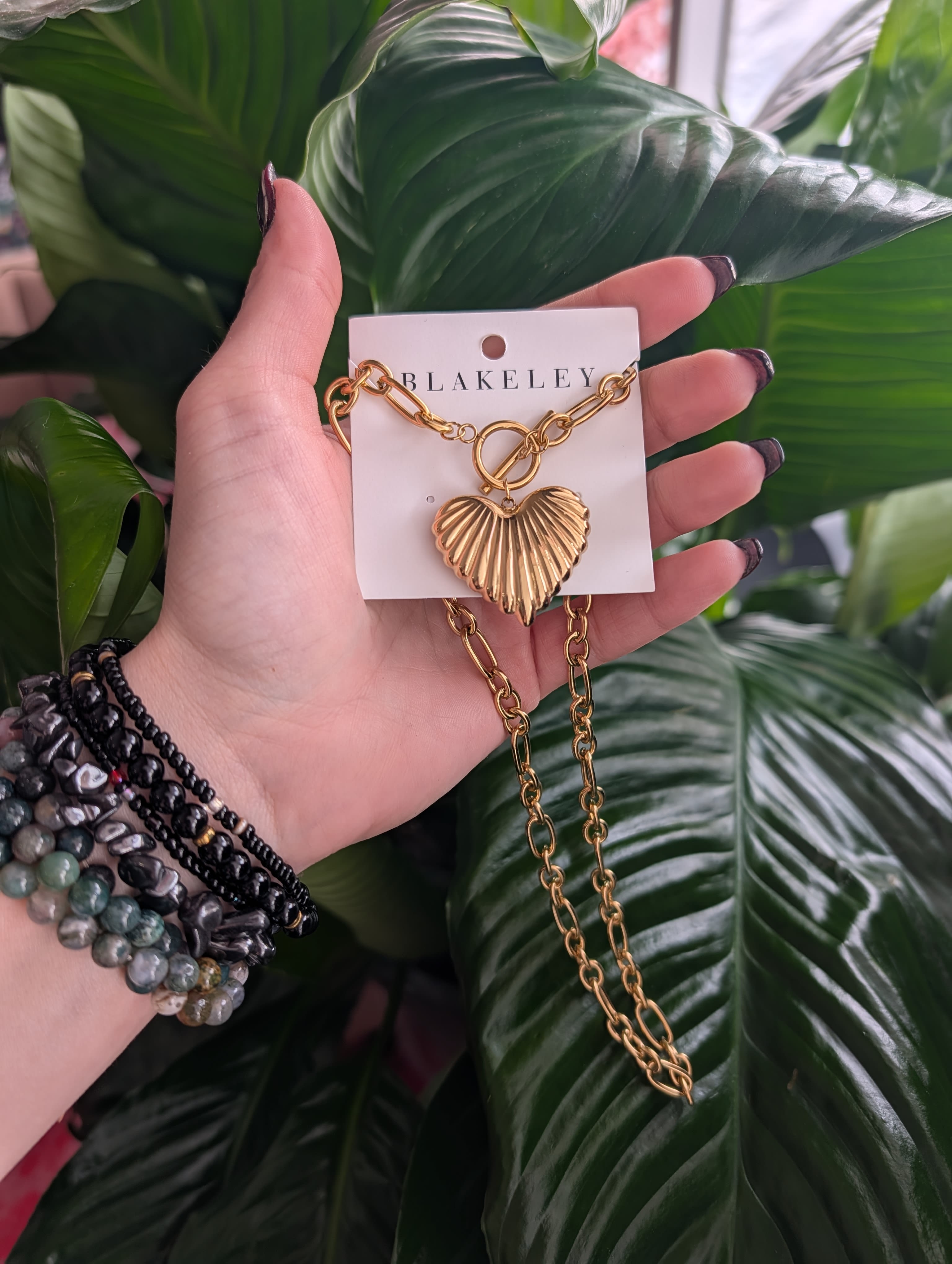 Hand holding a gold heart pendant necklace on a card