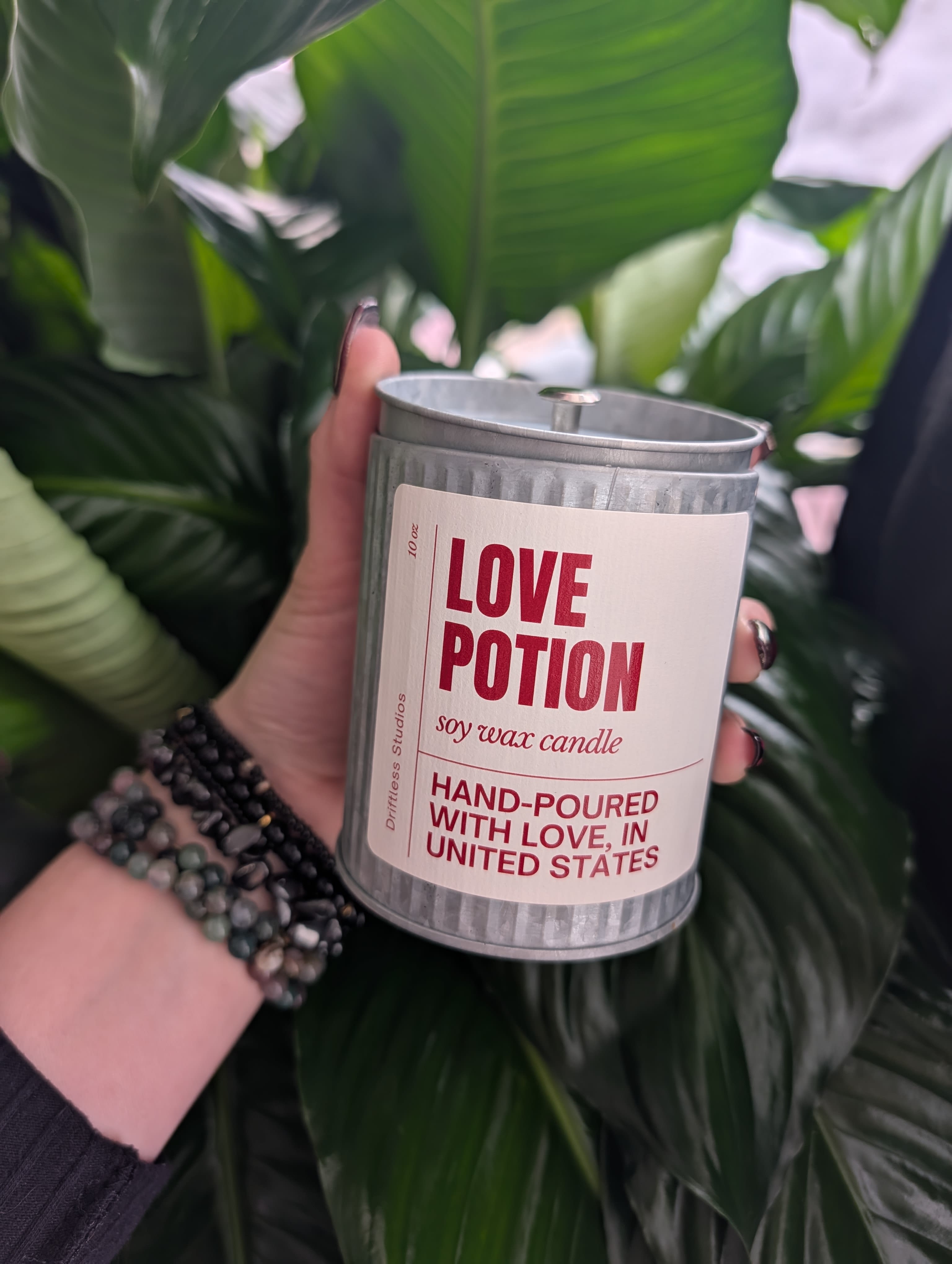 Handheld soy wax candle in a metal tin labeled Love Potion