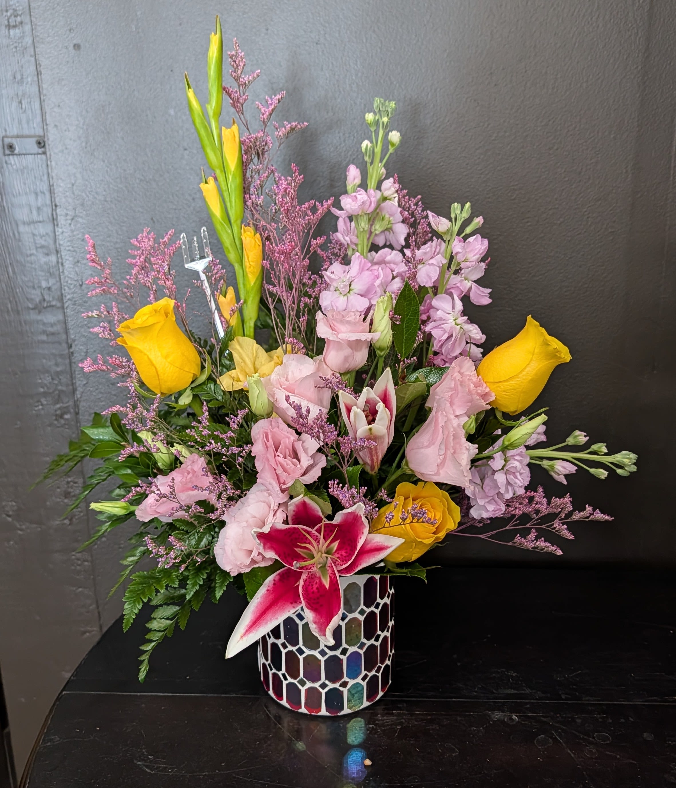 Mixed bouquet with yellow roses, pink lilies, and a mosaic vase