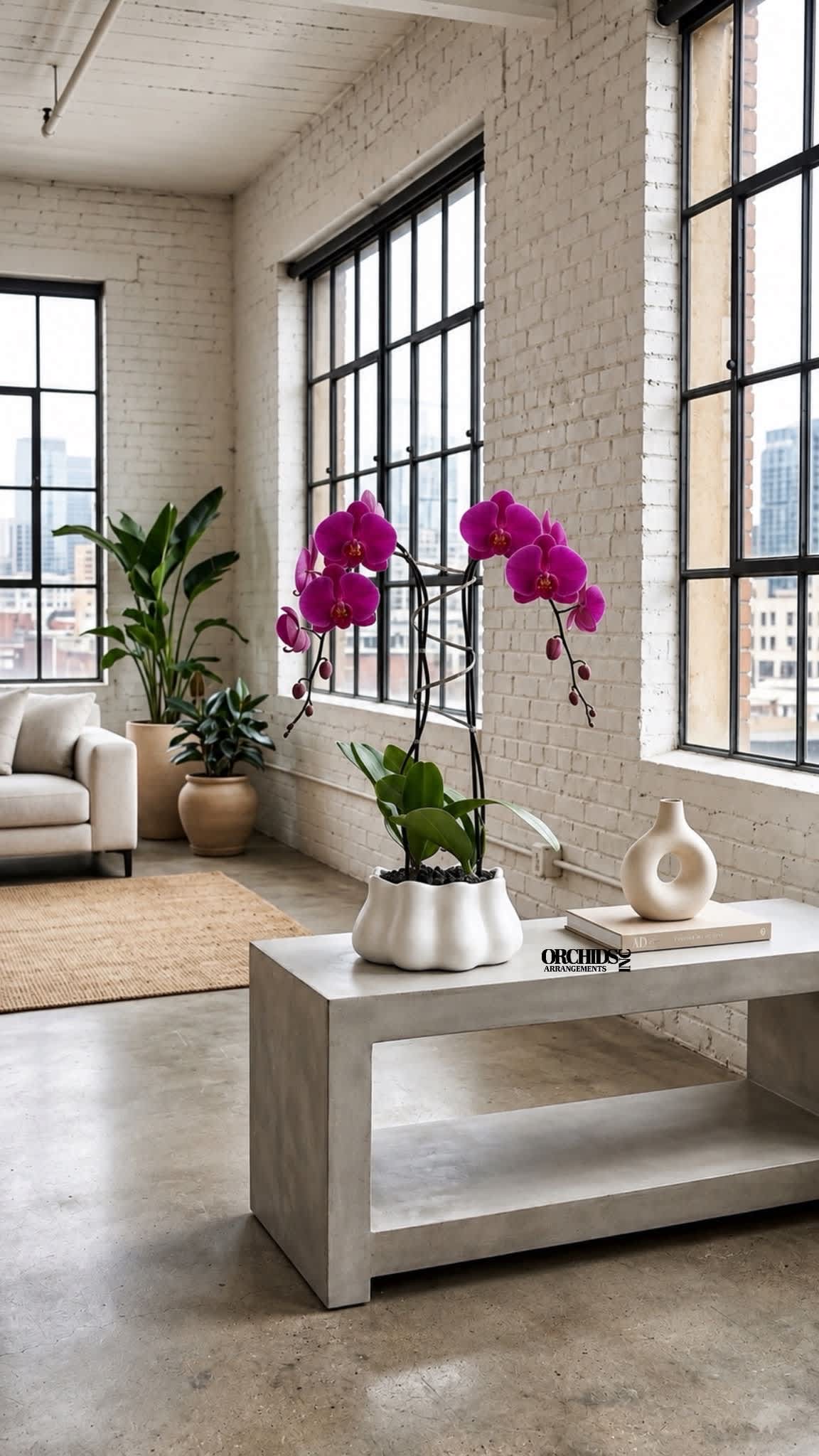 Potted purple orchids in a white planter on a concrete table