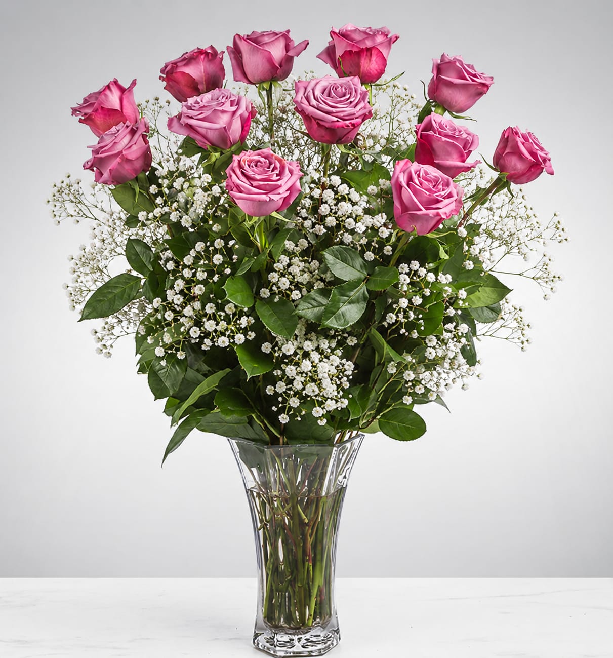 Pink roses arranged in a clear glass vase with small white filler flowers
