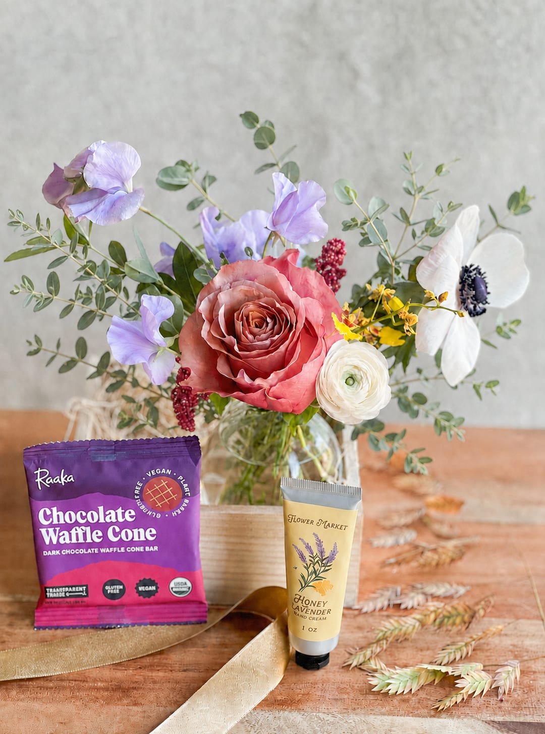 Bouquet in a glass vase with a chocolate bar and hand cream