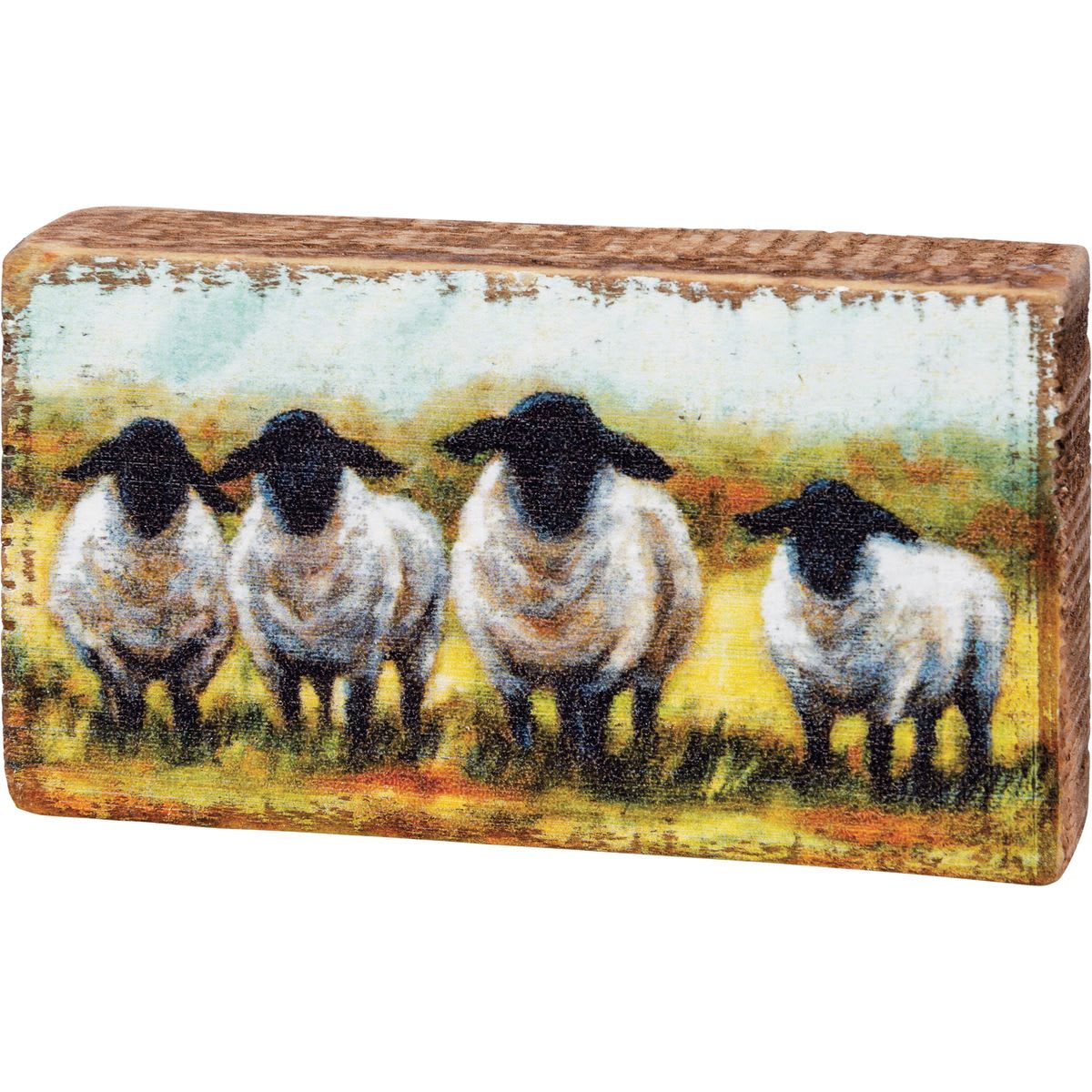Rectangular decorative block with painted sheep on a rustic wood surface