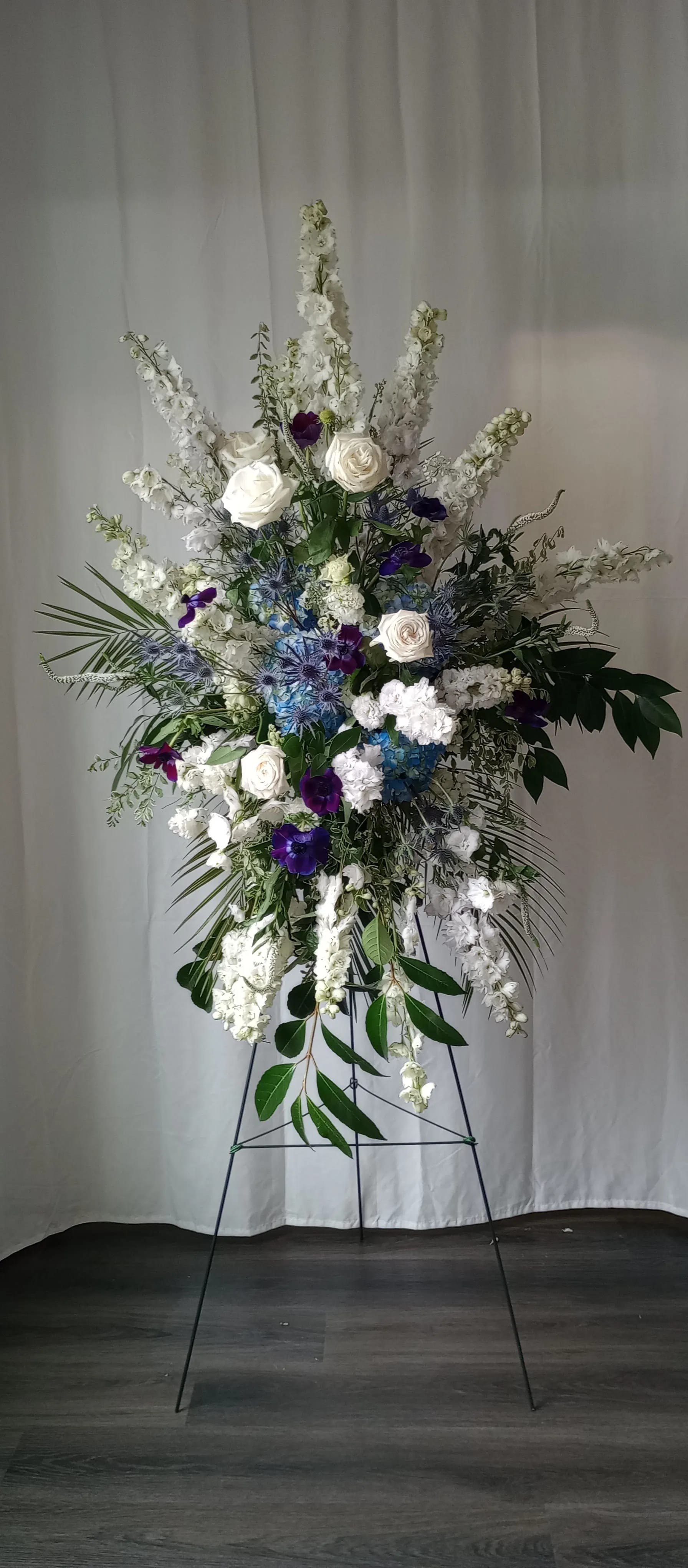 Tall white and purple floral spray on a black stand