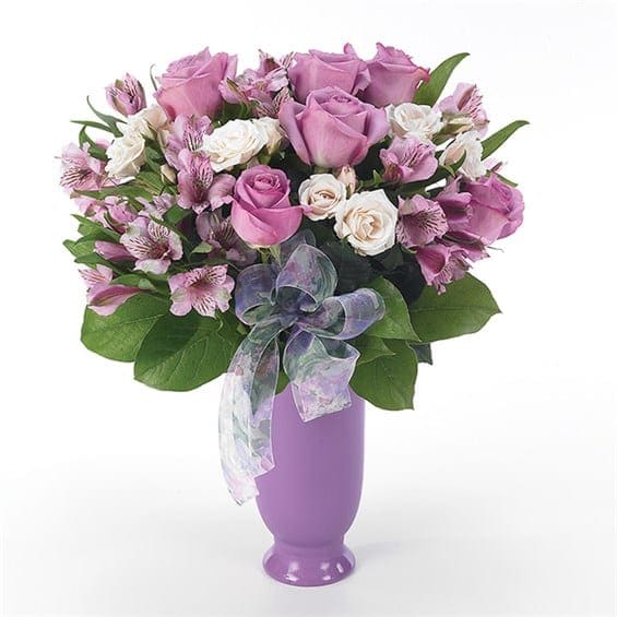 Garden Of Lavender Love - Show her everlasting love by sending a gift from the heart - an elegant purple arrangement of roses and alstroemeria in a purple vase. Measures 18"H by 12"L.