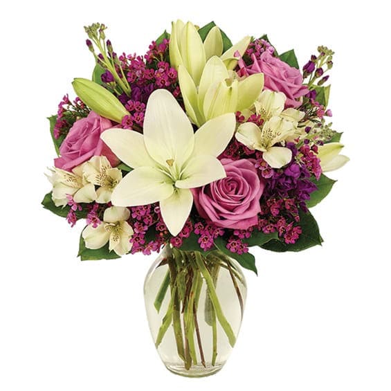 Lavender Elegance - Regal roses in elegant lavender mingle effortlessly with alstroemeria, waxflower and Asiatic lily to craft a bouquet of rare splendor that says love at first sight. Showcasing it all is a graceful clear vase. Measures 16”H X 13”L. Suggested Retail Price: $49.99.