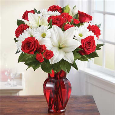 Red &amp; White Delight™ - EXCLUSIVE Delight them with red &amp; white. Our radiant new bouquet is a beautiful surprise for the one you love. Filled with lush blooms in classic romantic colors, this hand-gathered arrangement arrives in a striking ruby red vase, creating a memorable gift for an anniversary, or the everyday moments you want to hold onto forever. • All-around arrangement with red roses, carnations and mini carnations; white Asiatic lilies and daisy poms; accented with assorted greenery • Lilies may arrive in bud form and will open to full beauty over the next 2-3 days • Our florists select the freshest flowers available, so colors and varieties may vary due to local availability • Artistically designed in a ruby red vase; measures 8.75"H • Large arrangement measures approximately 20"H x 14"L • Medium arrangement measures approximately 19"H x 13"L • Small arrangement measures approximately 18"H x 12"L