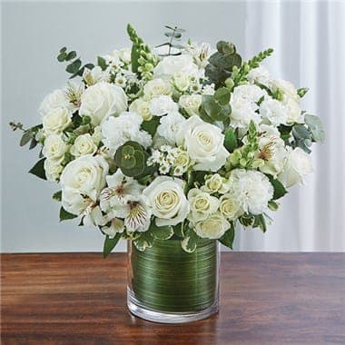 White roses and mixed white flowers in a green glass vase