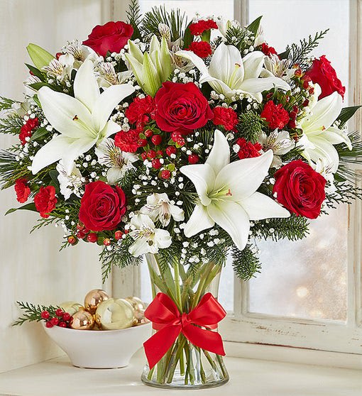 Bouquet of red roses and white lilies in a glass vase with a red ribbon