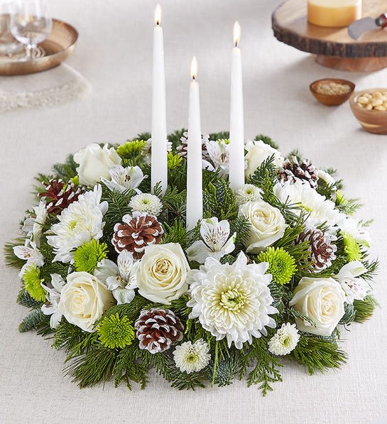 White floral candle centerpiece with pinecones and three taper candles