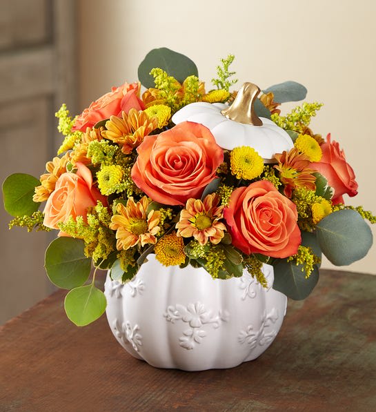 Orange roses and yellow mums arranged in a white pumpkin vase