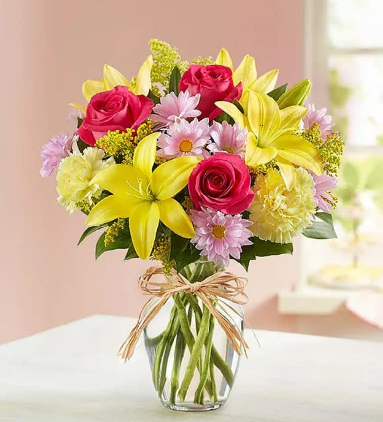 Bouquet of pink roses and yellow lilies in a clear glass vase