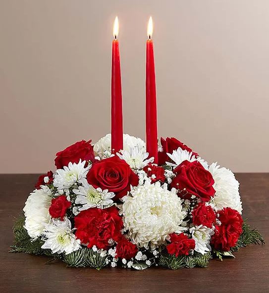 Red candles in a red, white, and green floral centerpiece