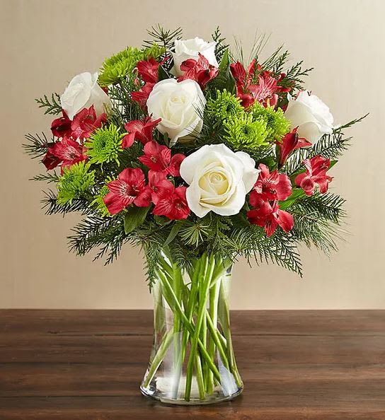 Bouquet of white roses and red flowers in a clear glass vase