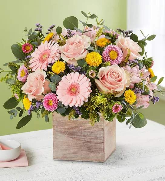 Pink roses and daisies arranged in a wooden box