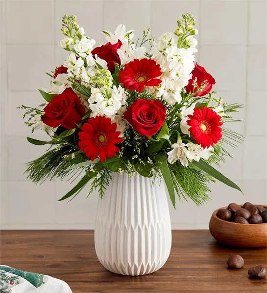 Red roses and gerbera daisies in a white vase